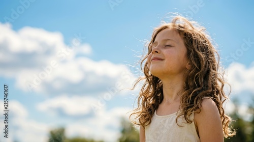 Happy young girl breathing fresh air and enjoying the sun on a bright summer day.