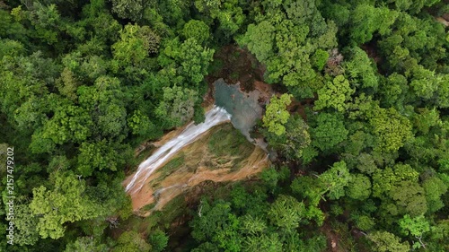 An aerial video showing a waterfall flowing from a mountain in the forest.