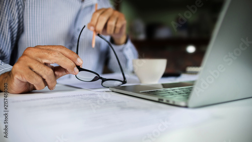 Foto close-up shot, businessman holding eyeglasses work on desk with laptop and docum