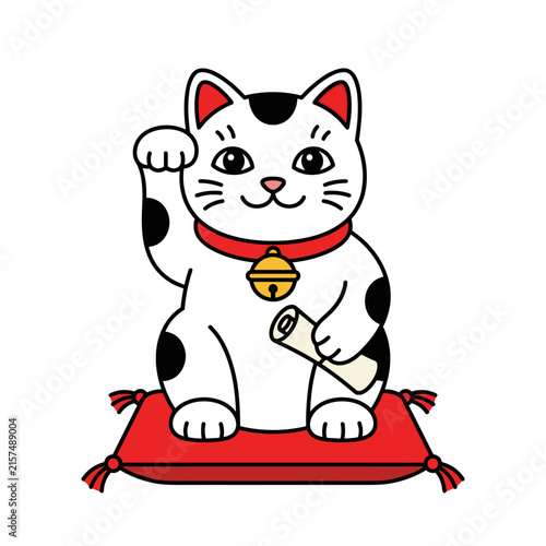 Cute beckoning cat figurine with traditional red collar and golden bell sitting on a cushion