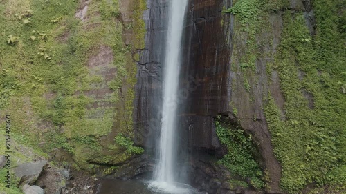 Majestic Waterfall Cascading Down Green Cliffs Surrounded by Lush Vegetation and Rocks