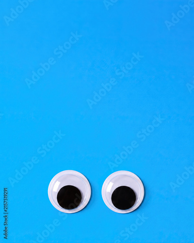 Two Googly Eyes Placed On A Bright Blue Solid Background