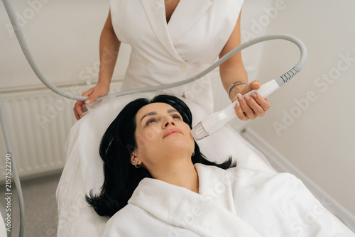 Quadro su tela Top view of middle-aged relaxed woman undergoing modern anti aging facial procedure, beautician applies microneedle rf device to skin for non invasive lift and rejuvenation treatment
