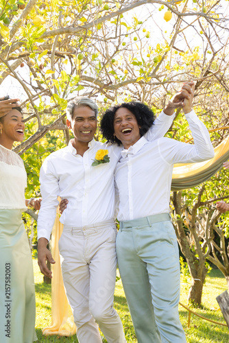 African grooms walking grass aisle under lemon trees in white shirts rose pin phone fabric arch