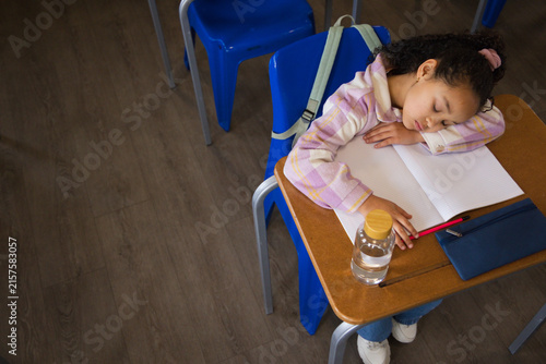 African American teenage student sleeping at classroom desk with notebook and pencil, copy space