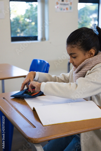 African-American schoolage student sitting at desk-slot opening pencilcase and notebook, copy space