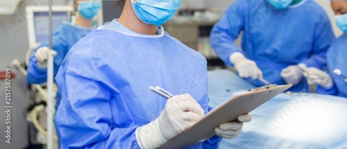 Surgeon Writing on Clipboard During Surgery in Operating Room