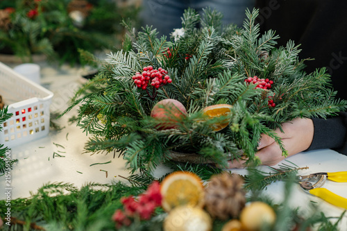Hands using pruning shears to cut evergreen branches for a handmade christmas wreath