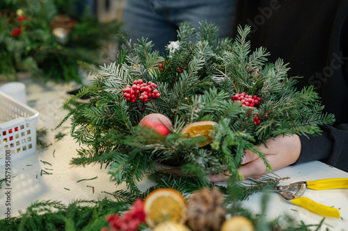 Hands using pruning shears to cut evergreen branches for a handmade christmas wreath