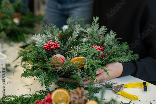 Hands using pruning shears to cut evergreen branches for a handmade christmas wreath
