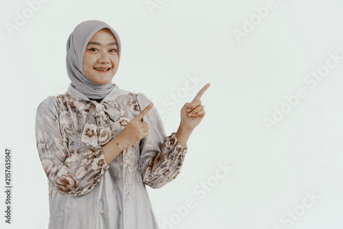 Portrait happy young asian muslim female standing on isolated pointing finger hands to blank space for text advertisement. Beautiful Attractive Muslim woman wearing hijab fashion costume.