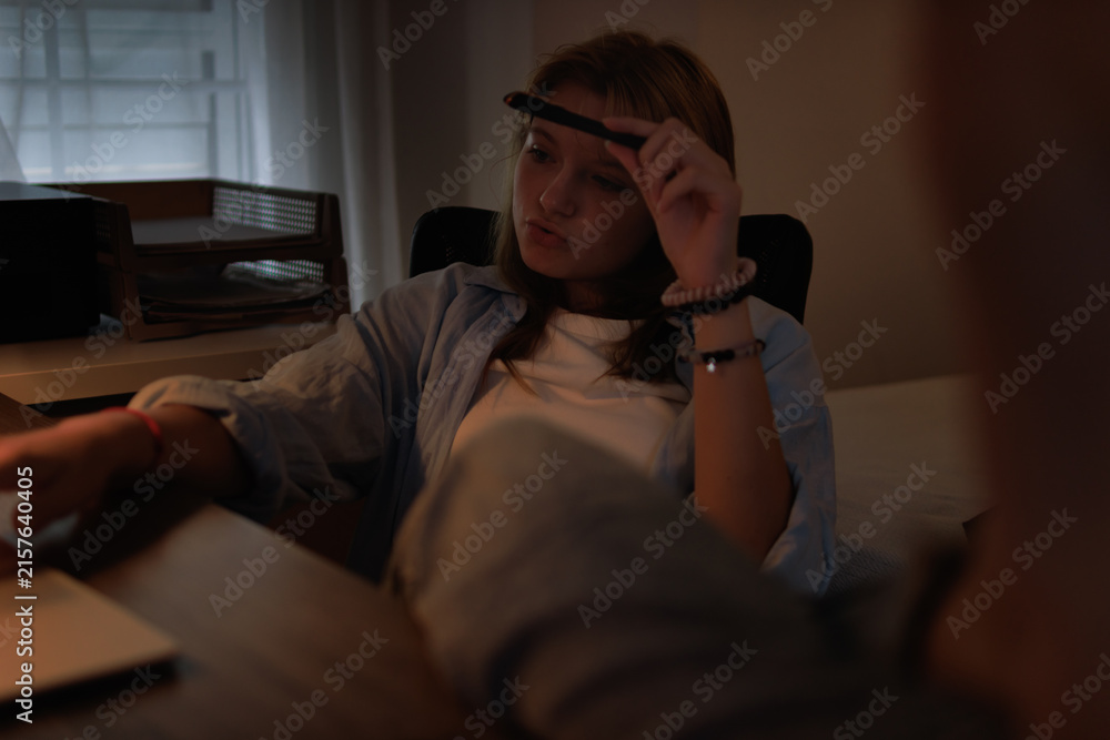 Fototapeta premium Teenager student studying at home office late at night, thinking deeply while learning, focused on academic work, back to school education concept