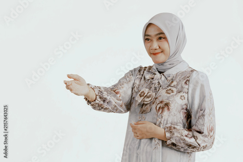 Smiling asian female muslim in headscarf with offering gesture with space.
