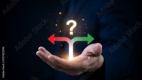 Plakat Businessman holding glowing question mark and split direction arrows