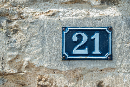 House number 21 plaque on a textured stone wall with generous copy space on the left.