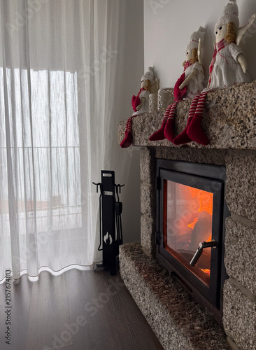 burning fireplace with christmas elves, cozy home interior, window, copyspace for text, concept of holiday decor, home goods