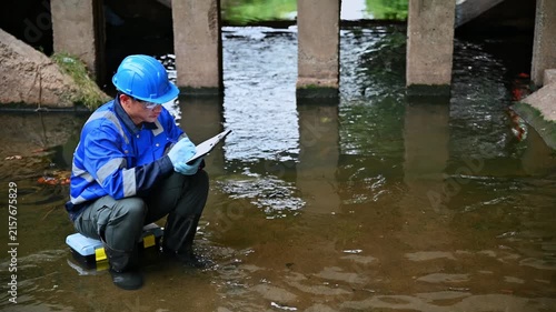 Environmental worker inspecting wastewater and collecting water samples at an industrial treatment facility
