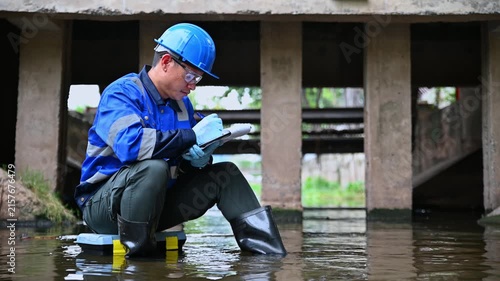 Environmental worker inspecting wastewater and collecting water samples at an industrial treatment facility