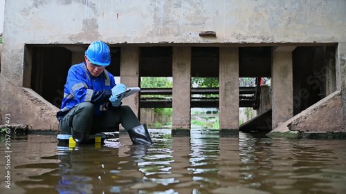 Environmental worker inspecting wastewater and collecting water samples at an industrial treatment facility
