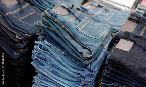 Stacks of blue jeans in various shades, showcasing denim texture, stitching, pockets, fashion apparel, retail, and shopping concepts
