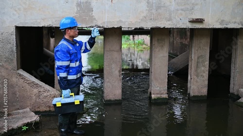 Environmental technician monitoring water quality and collecting samples from an industrial water system