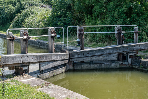 Traditional wooden lock gates and mechanical gear system on a navigable canal in the English countryside.
