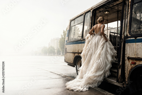 Bride in a white gown boards an old bus. Space for text.