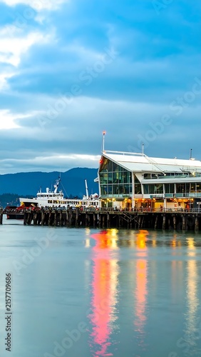 Modern waterfront city skyline with reflections and boats.
