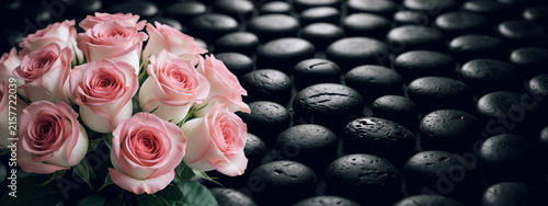 Mazzo di rose dal tenue colore bianco rosa che spiccano su uno sfondo di pietre dalla texture scura e liscia