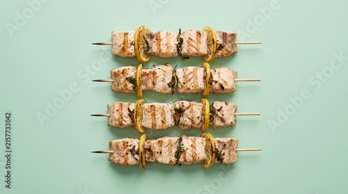 Grilled fish skewers rest on a green background.