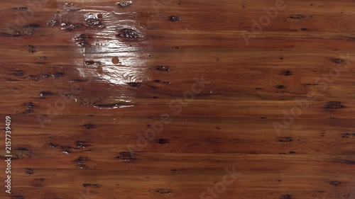 Close-up slow motion water droplet splashing on dark stained wooden surface texture