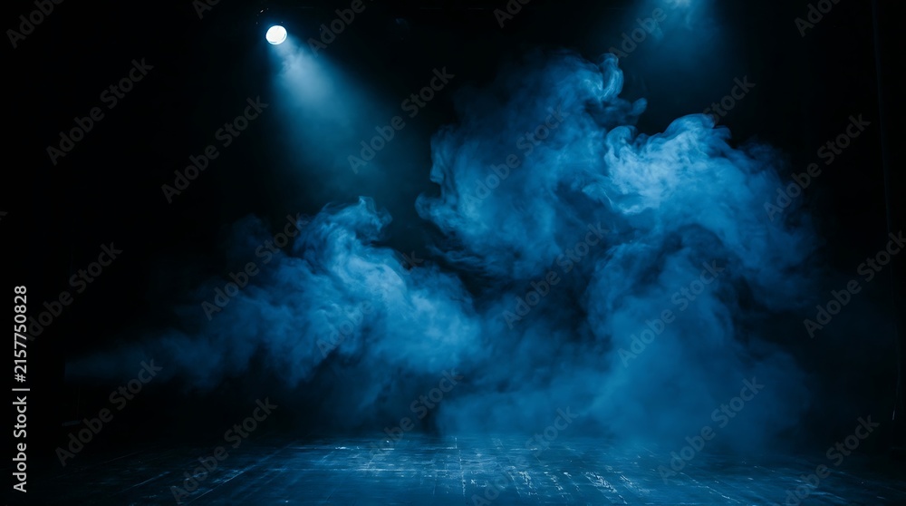 Fototapeta premium Bright blue spotlight shining on stage smoke in a dark theater