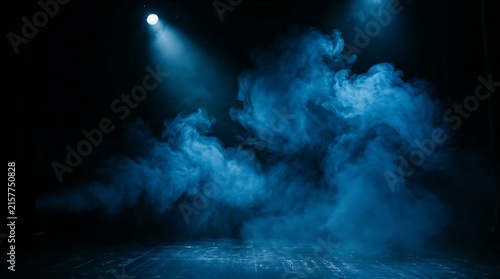 Bright blue spotlight shining on stage smoke in a dark theater