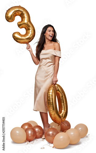 Happy woman celebrating thirtieth birthday holding large gold number thirty balloons with thirty year old, birthday part