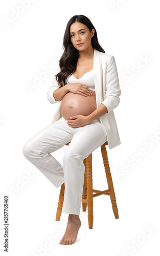 Pregnant woman in white clothing touching her belly while sitting on a stool one person white background pregnant