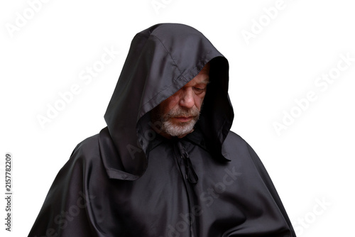 Serious hooded older man in black cloak looking down isolated