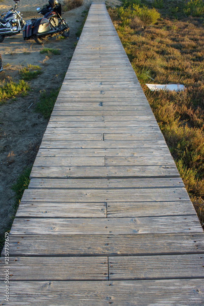 Obraz premium Sturdy wooden walkway leads through serene landscape at sunset, inviting exploration and tranquility