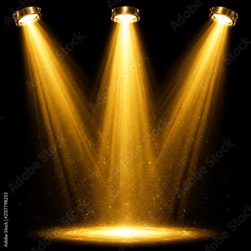 Three bright golden spotlights shining down on a dark stage creating dramatic atmosphere and light beams