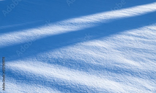 Sunlit snow drifts casting long, diagonal shadows