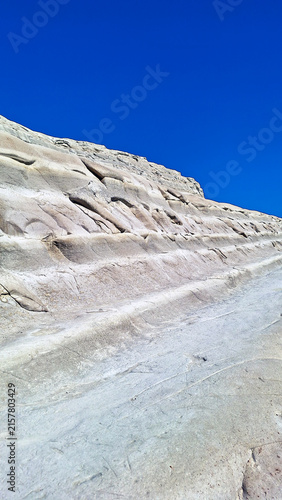 Vertical close shot of the unique stepped limestone formations at Scala dei Turchi in Realmonte, Agrigento, Sicily, showing the smooth white geological layers under a clear summer sky.