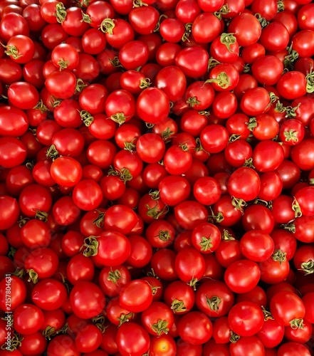 Full frame top view close up shot of vibrant fresh red cherry tomatoes with green stems.