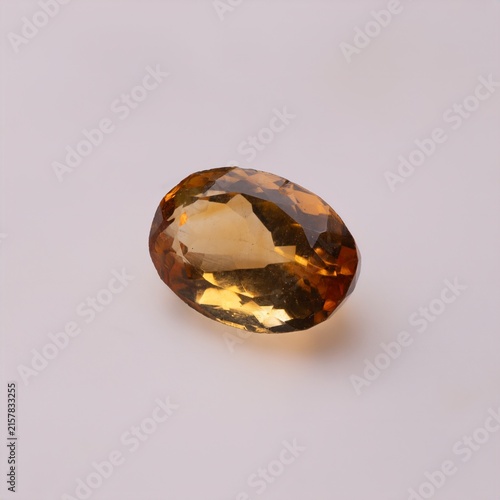 Fotografie Oval cut yellow citrine gemstone with faceted surfaces on a plain white background