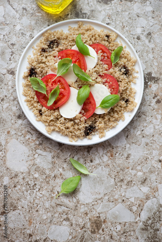 Italian caprese with quinoa on a light-brown granite background, vertical shot, copyspace, above view