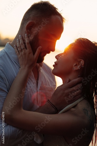 Foto Romantic couple embracing at sunset, young lovers touching faces tenderly in gol