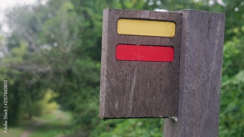 Wooden trail marker with yellow and red painted stripes