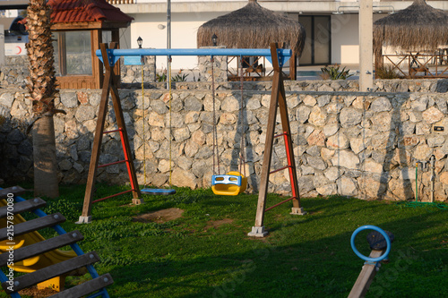 Foto Children's swings swaying gently in the evening light at a serene playground by