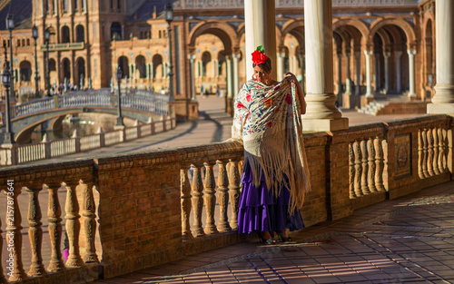 the beautiful girl in the square wraps herself in her splendid Andalusian shawl