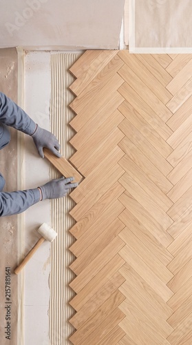 Worker installing oak wood parquet floor in herringbone pattern