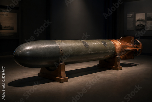 Decommissioned naval torpedo on wooden display cradles in museum, naval history concept