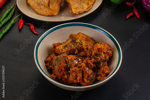 Quadro su tela Spicy curry dish with fried bread and fresh chilies on dark surface